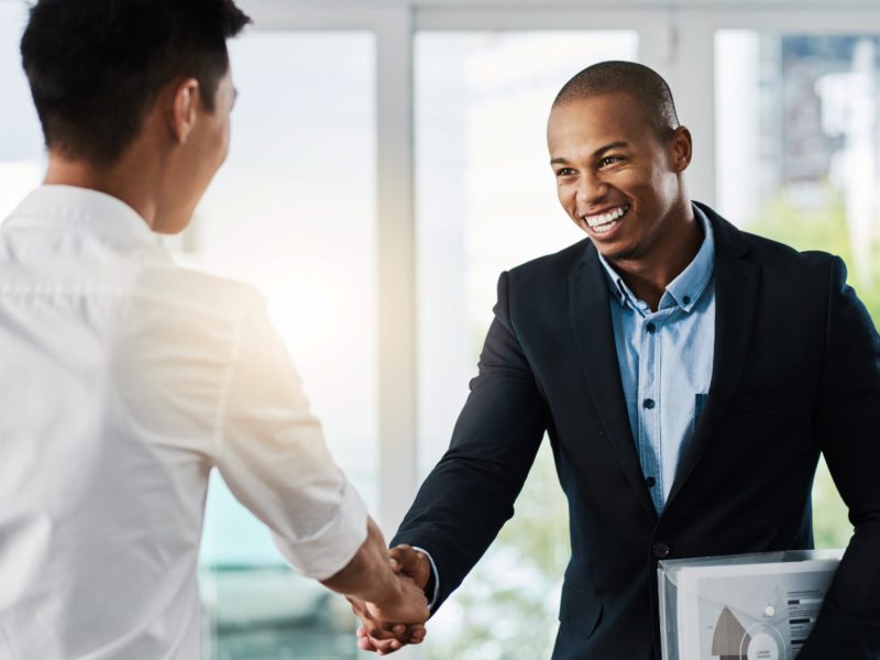 Shot of two young businessmen shaking hands in a modern office